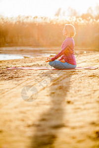 年轻女子在湖外露室附近做瑜伽冥想运动健身和自然锻图片