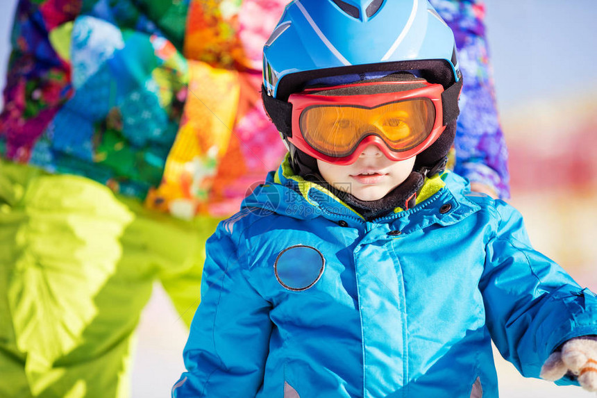 穿着滑雪头盔和护目镜父亲或教官的滑雪小滑雪图片