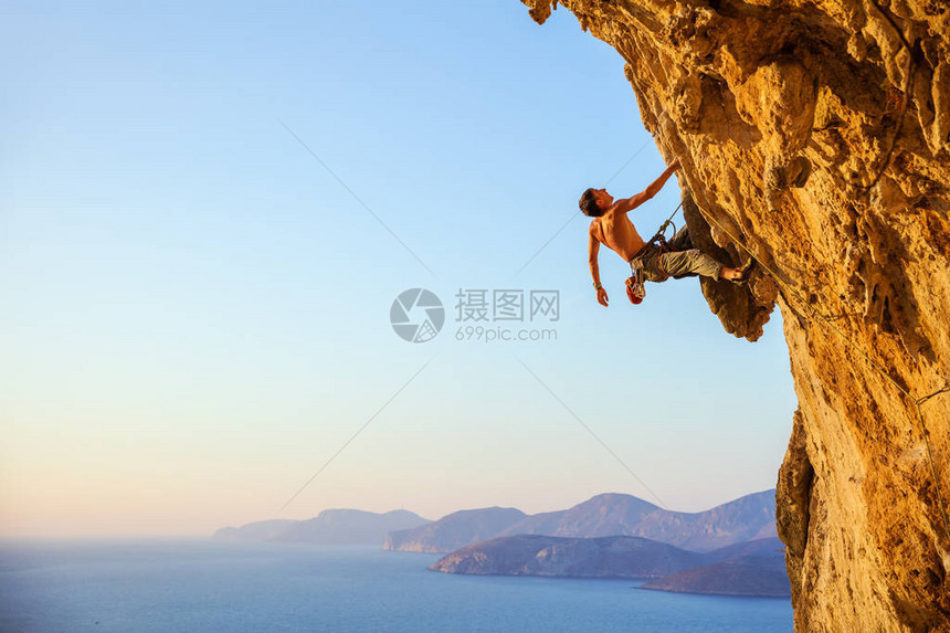 年轻男子在悬崖上攀爬挑战路图片