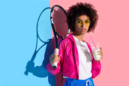年轻明亮的非洲女孩拿着网球拍打和塑料杯图片