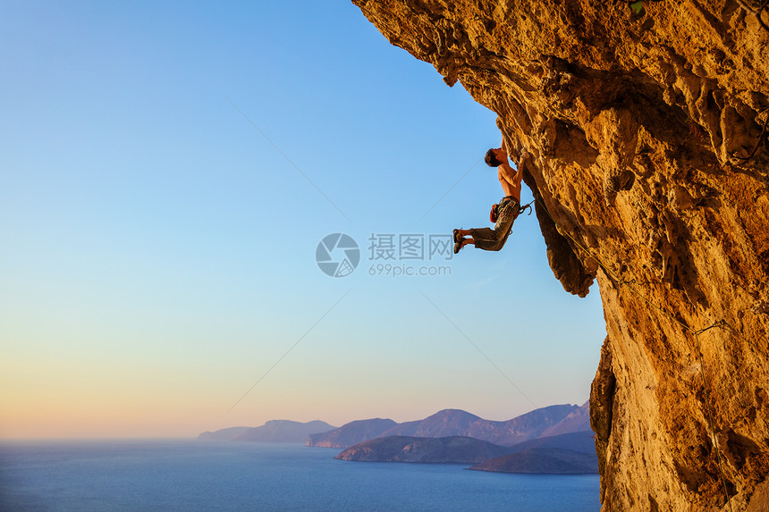 攀岩者在攀登悬垂的悬崖时在扶手上跳跃图片