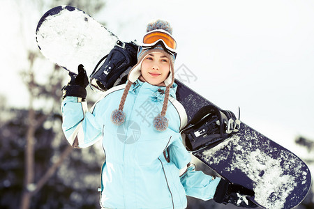 年轻女子肩上举着滑雪板图片