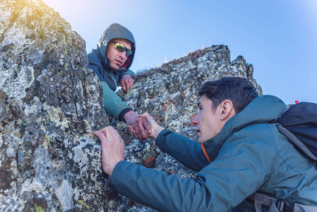一个男人帮助他的朋友爬上山顶希克帮人图片