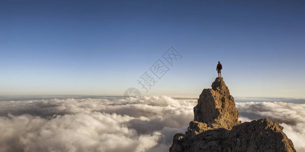 人类在云层之上的山顶上背景图片