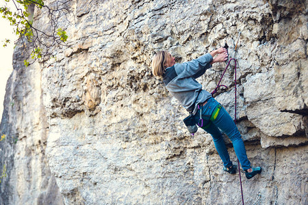 女孩爬上岩石在大自然和攀岩中健身女人爬上去积极的生活方式岩图片