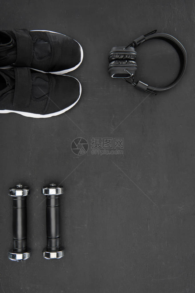 黑色背景中的运动鞋哑铃和耳机图片