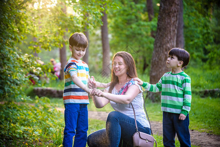 年轻女子母亲在美丽的夏日或傍晚的森林远足前给她的两个儿子使用驱虫剂夏季保护儿童免受昆虫叮咬与孩子背景图片