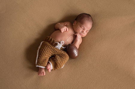 一个睡着的九天大的新生婴儿男孩穿着围网图片