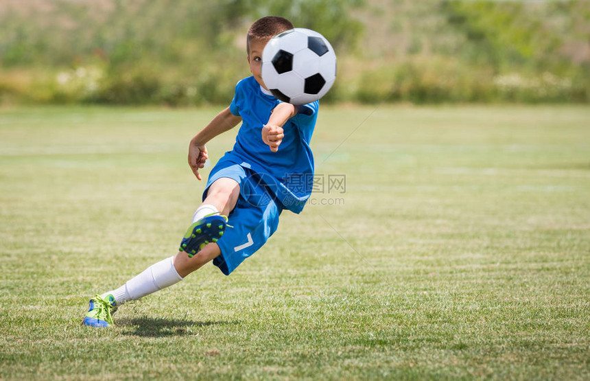 男孩在运动场上踢足球图片