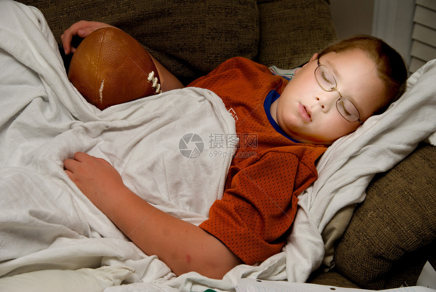 一个小男孩抱着他的足球睡觉图片
