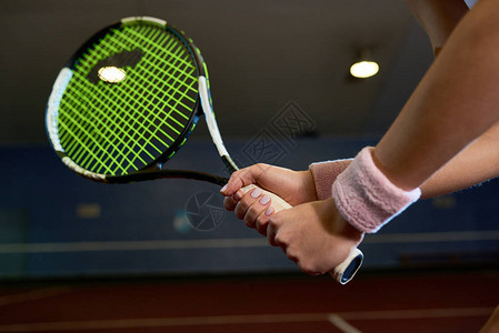 在室内法庭打网球和挥棒打球时握着电击手的近距离接近无背景图片