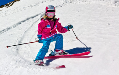 女孩在雪地上滑雪在山上阳光明媚的一天在图片