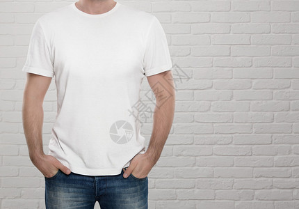 男子在白砖墙上穿着空白的T恤衫背景图片