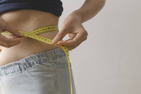 年轻女用测量胶带测量腰部减肥的概图片