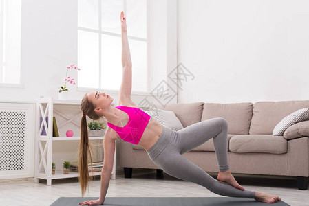 健壮女人在家的木板上练瑜伽年轻瘦弱图片