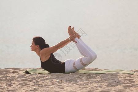 女人在沙滩上练瑜伽达努拉萨纳鞠躬姿势户外运图片