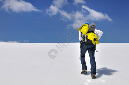 徒步旅行者在蔚蓝的天空下攀登一座雪山图片