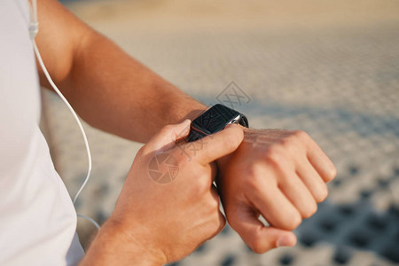 年轻的跑步者在可穿戴的智能手表电脑设备上做手势图片