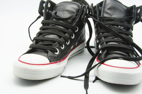 一双白色背景上的黑色皮革运动鞋图片