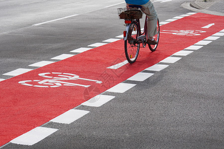 卡里尔无法辨认的骑自行车者在红色自行车道上骑自背景