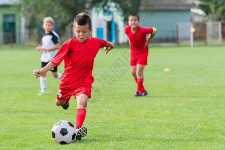 男孩在运动场上踢足球背景图片
