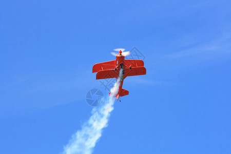 双翼运动飞机使用烟雾轨迹进行示范航背景图片
