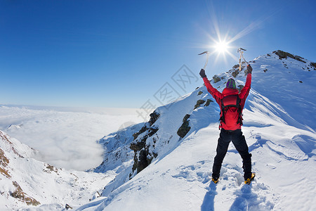 登山者在一个阳光明媚的冬日到达一座雪山之巅图片