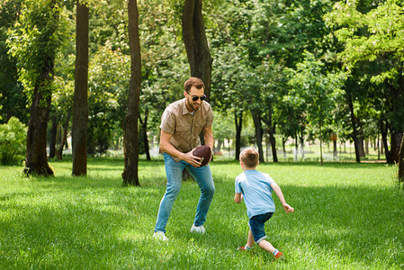 父亲和儿子一起在公园踢图片