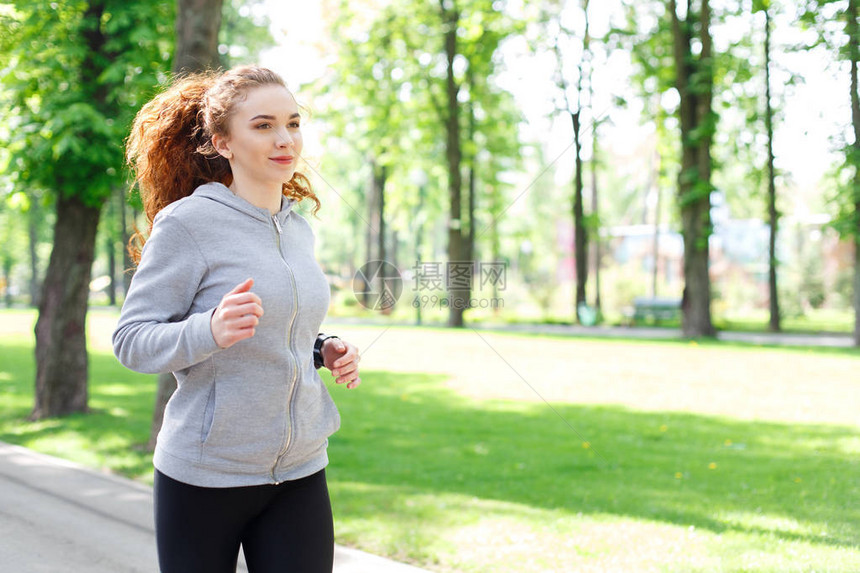 清晨运动时在绿色公园跑的年轻运动女青图片