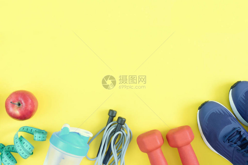 黄色背景上的运动器材哑铃绳索瓶子和运动鞋精美地展开健身背景与文本空图片