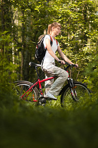 在森林中骑自行车的美丽的年轻美女您文字图片
