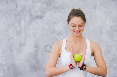 快乐的女运动家坐在瑜伽垫子上坐着苹果图片