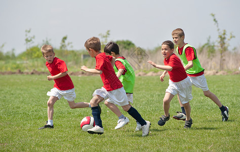 在运动场上踢足球的小男孩图片