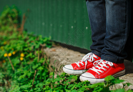 红鞋子红运动鞋穿混凝土在灌木之间视背景