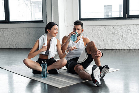 运动青年夫妇饮用水在健身后休息图片