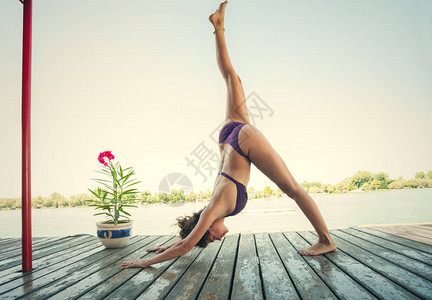 夏季瑜伽年轻女子在木制河筏上穿着比基尼做瑜伽图片