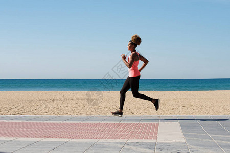 长的非洲年轻女子在海滩上跑动图片