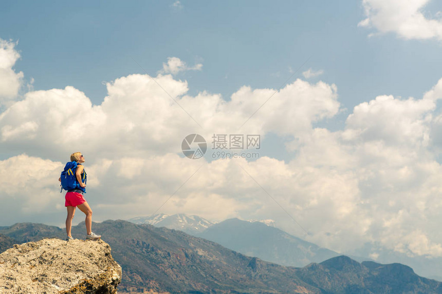 在美丽的鼓舞人心的山日出中庆祝或祈祷的女人在山顶远足或登山的女孩徒步旅行者在岩石上图片