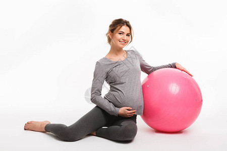 年轻快乐的怀孕少女坐在健身球里图片