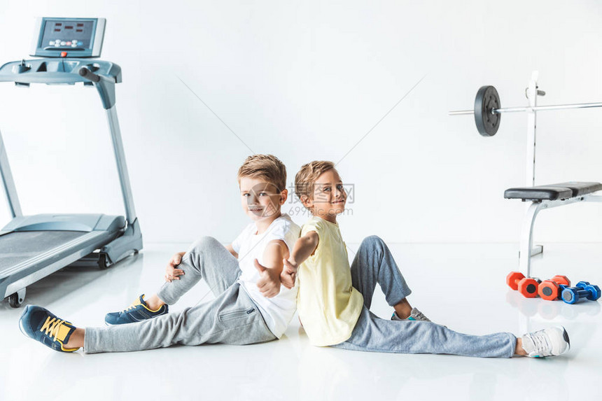 可爱的小男孩们在健身房的摄影机上举图片
