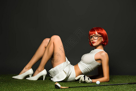 穿着高跟鞋和裙子的年轻美女躺在绿色草地上高尔夫图片