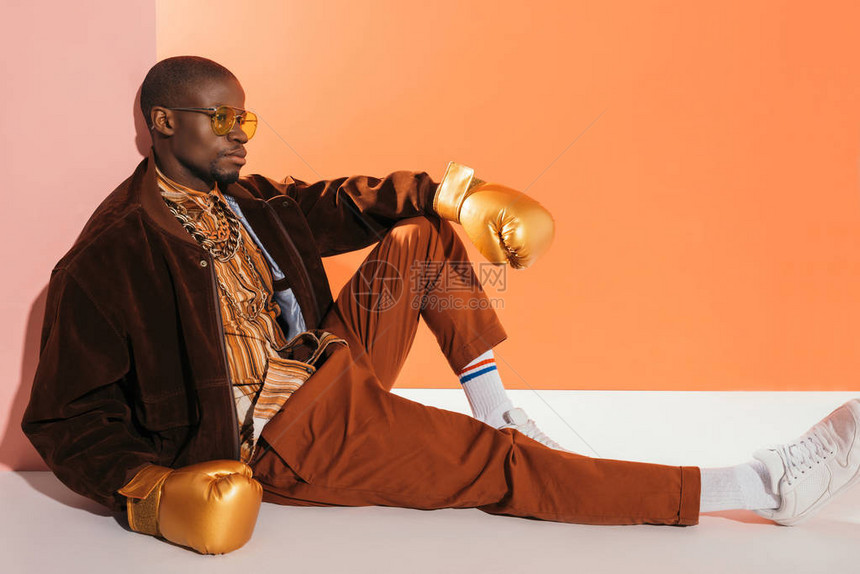 身戴太阳眼镜和金拳击手套的时尚的非洲男子图片