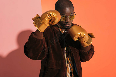 身穿金手套拳击和看摄影机的年轻非裔美国人男子图片