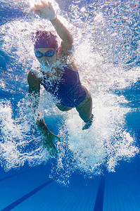前爬水下年轻女游泳者图片