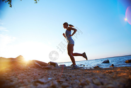 年轻女子在日出时在海滩图片