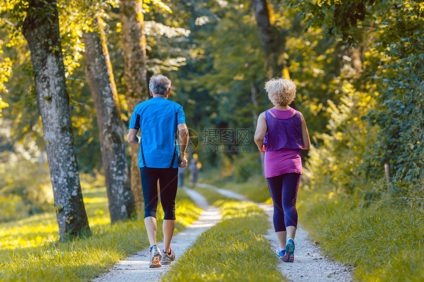 一对穿着酷跑装的年长夫妇在夏季在公园里漫步到户外在田间图片