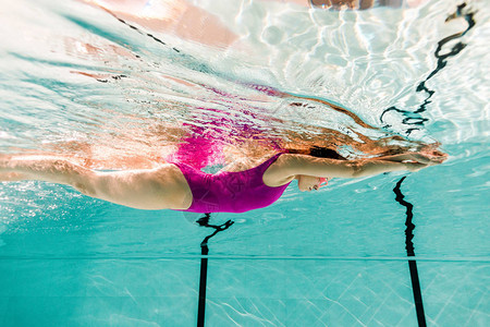 女人在蓝色水的游泳池里游泳图片