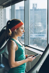 运动妇女在健身房使用智能手机和耳机图片