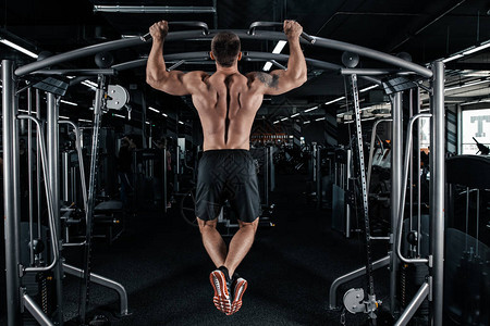 肌肉男做引体向上运动的背影图片