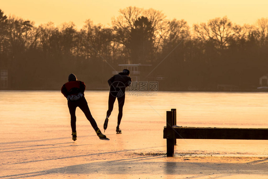 在荷兰冰冻湖上晒太阳的橙色夜晚亮光下图片
